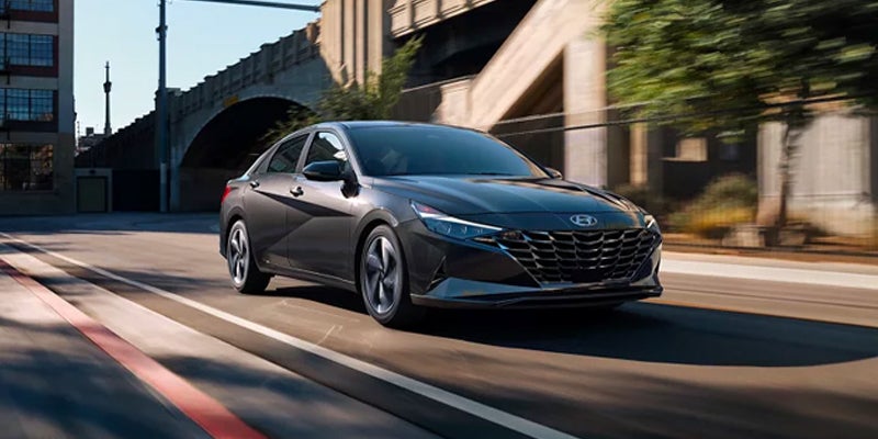 Gray Hyundai sedan driving on a city street in daylight