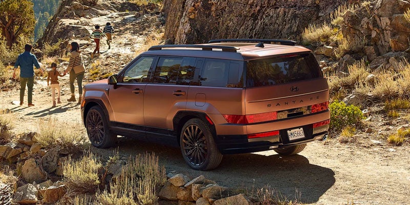 Hyundai Santa Fe SUV driving on a rocky dirt trail in a desert landscape