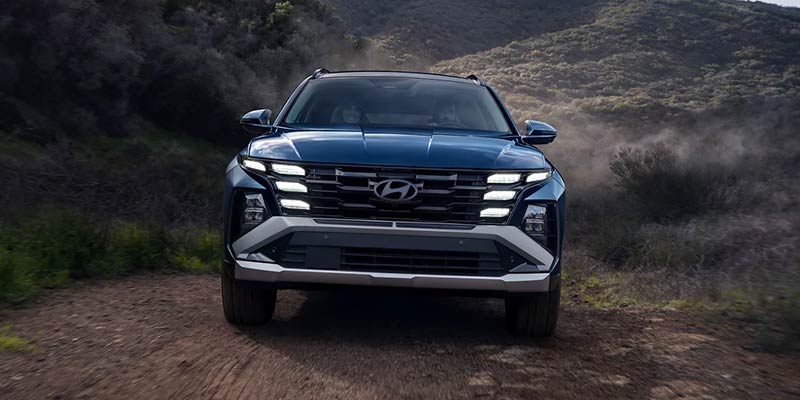 Hyundai SUV driving on a dirt road in a mountainous landscape