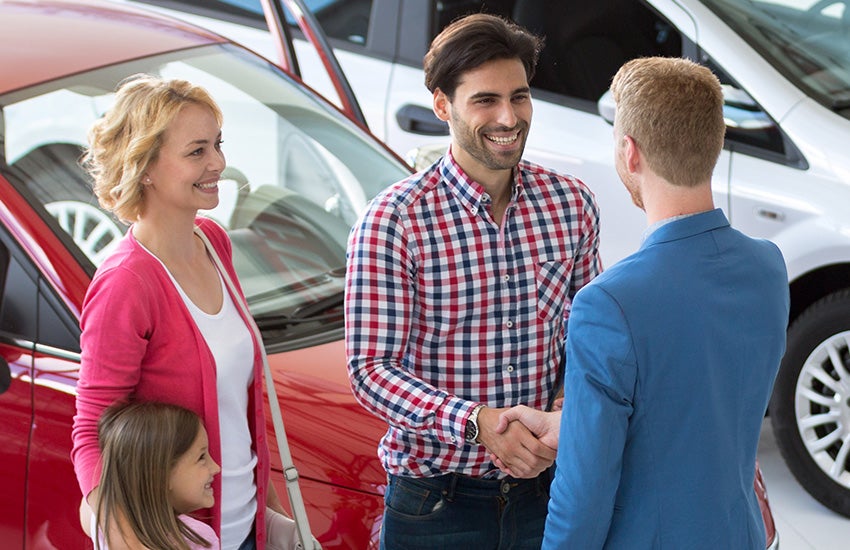 family is shaking hands with employee at dealership